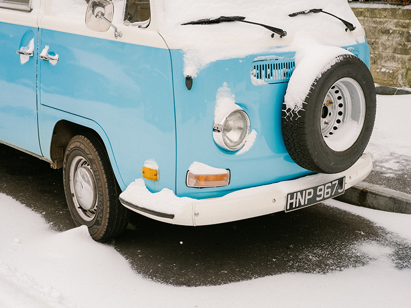 Blau-weißer Campingbus mit Ersatzrad und Schnee